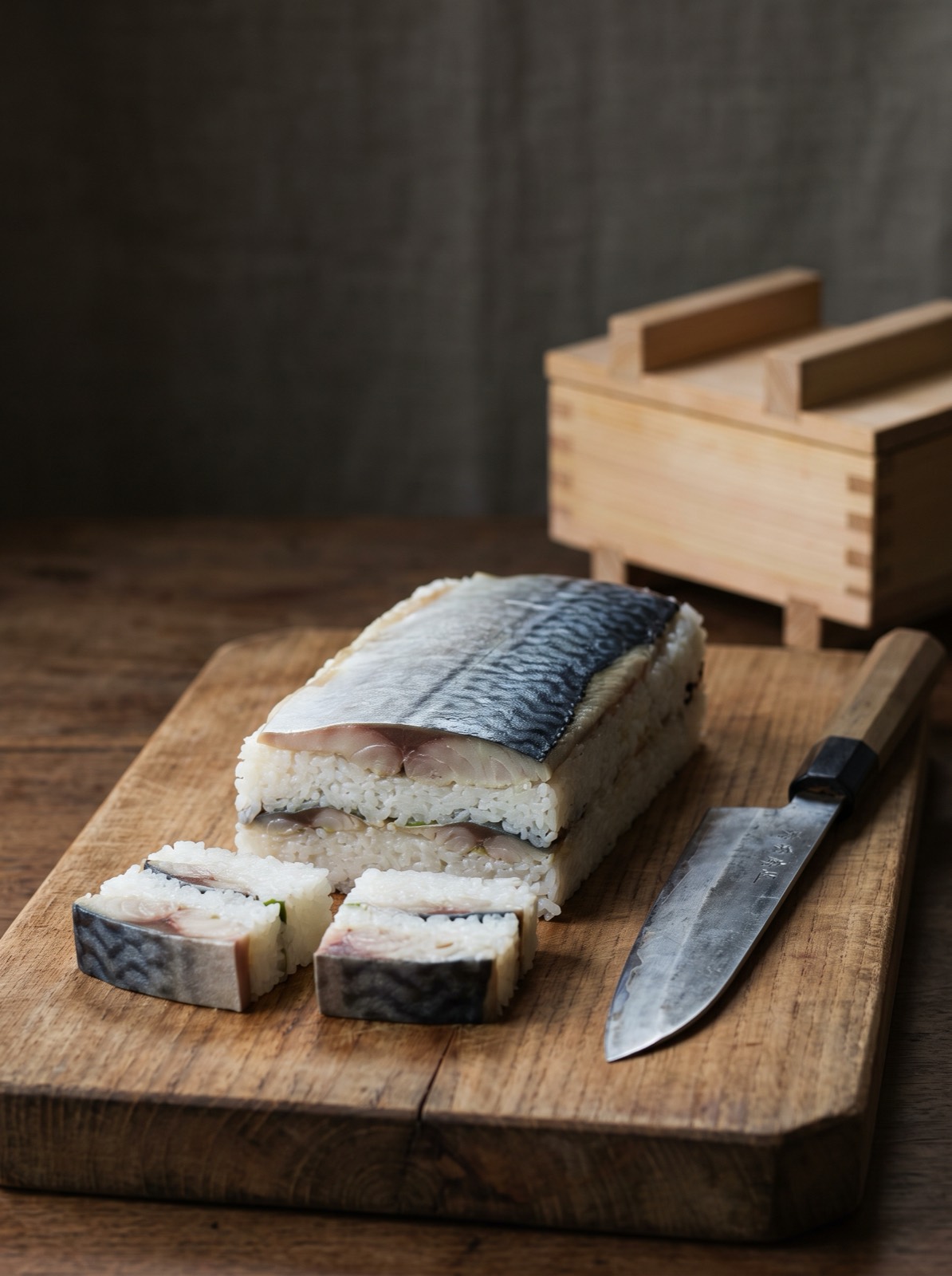 Pressed box sushi being cut into squares.