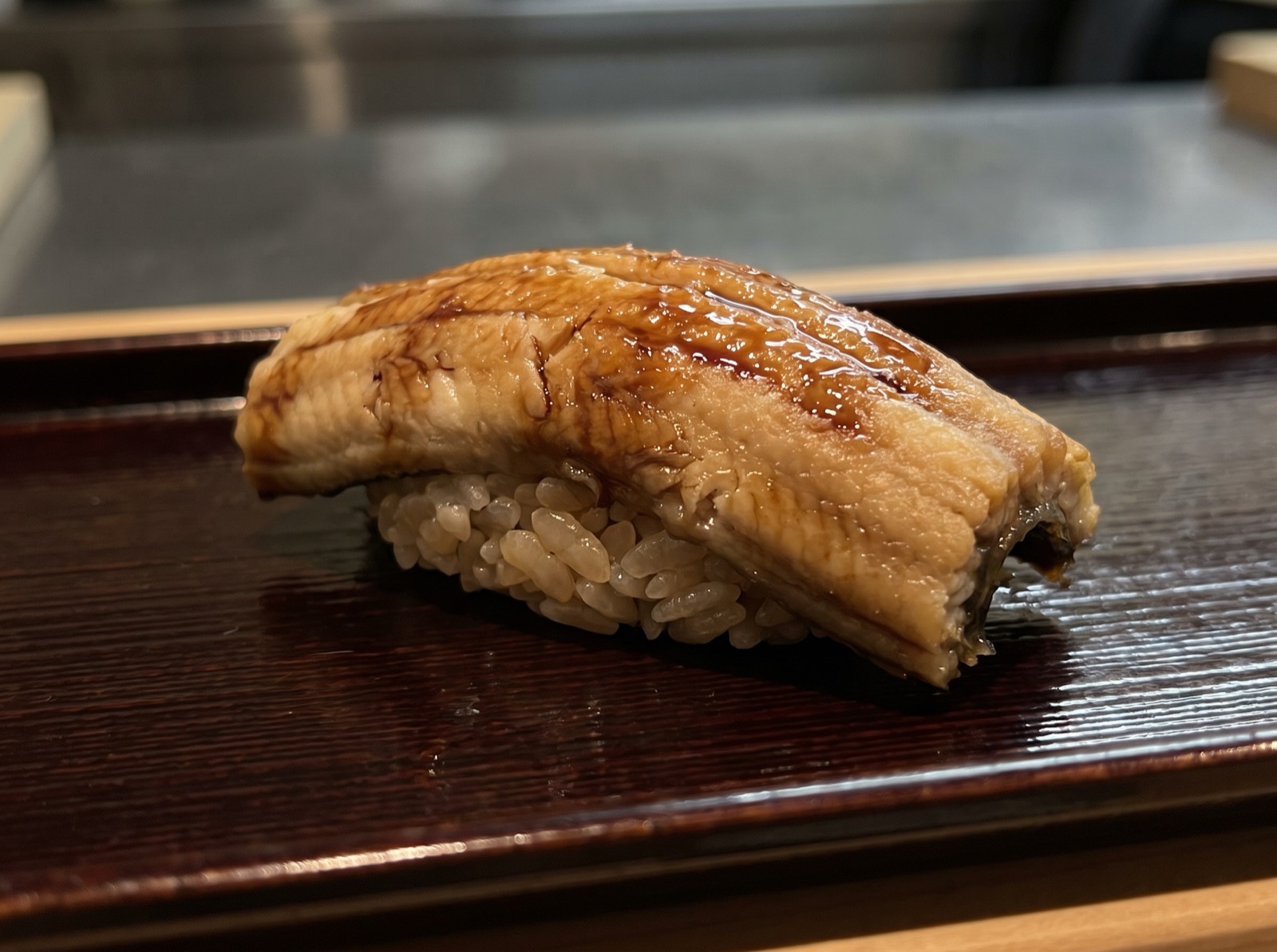 Simmered conger eel nigiri, glazed with sweet tsume sauce.