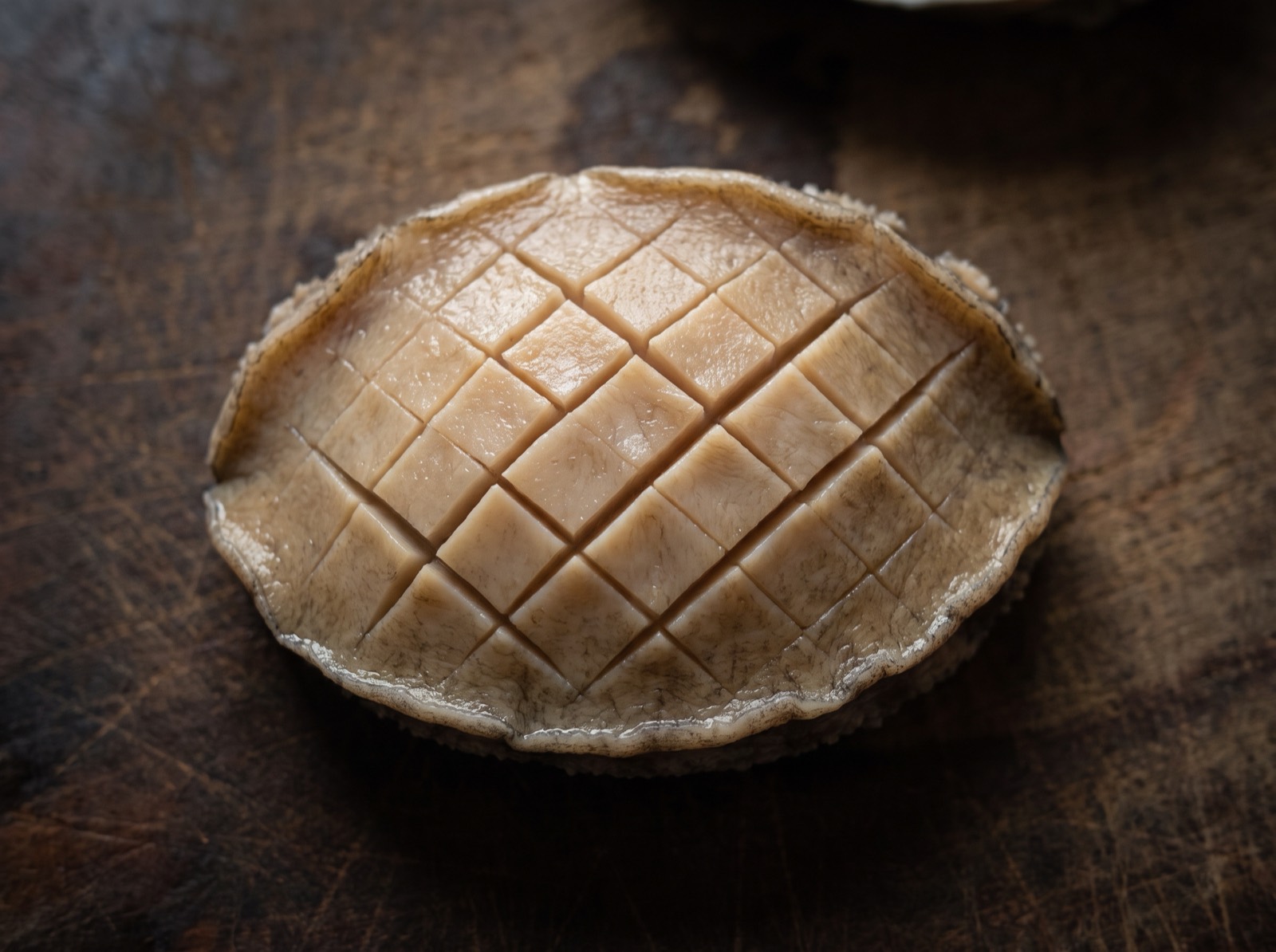 Awabi, flesh removed from its shell and scored in a fine lattice.