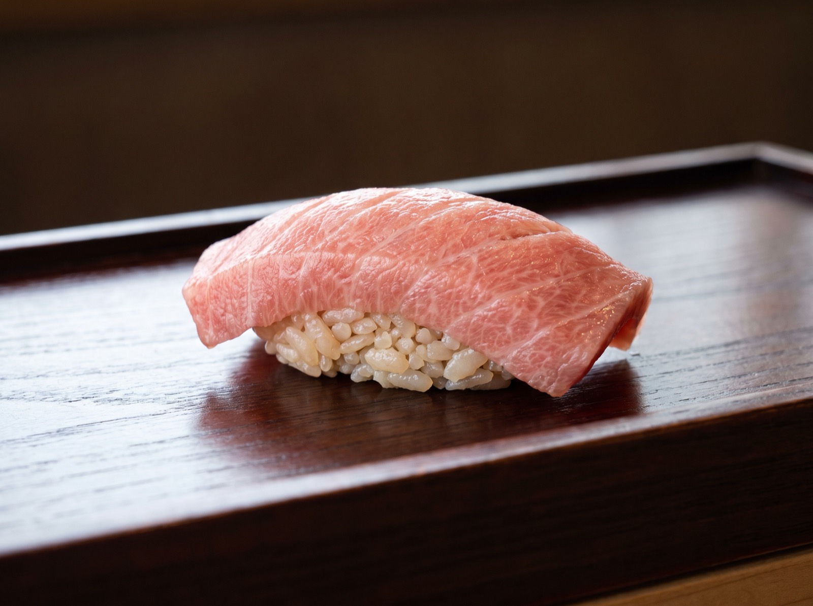 Chutoro nigiri, pink flesh with fine parallel fat lines.