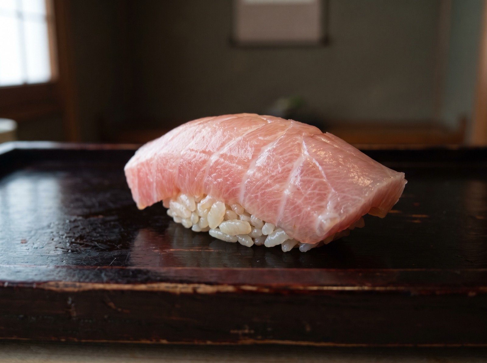 Hamachi nigiri, showing white fat lines through pink flesh.