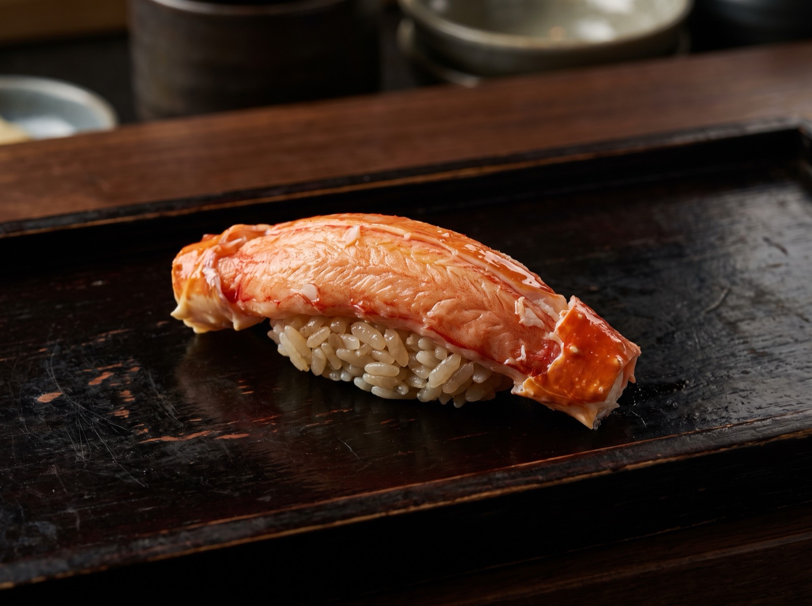 Kani nigiri, a whole boiled crab leg laid straight across the rice.