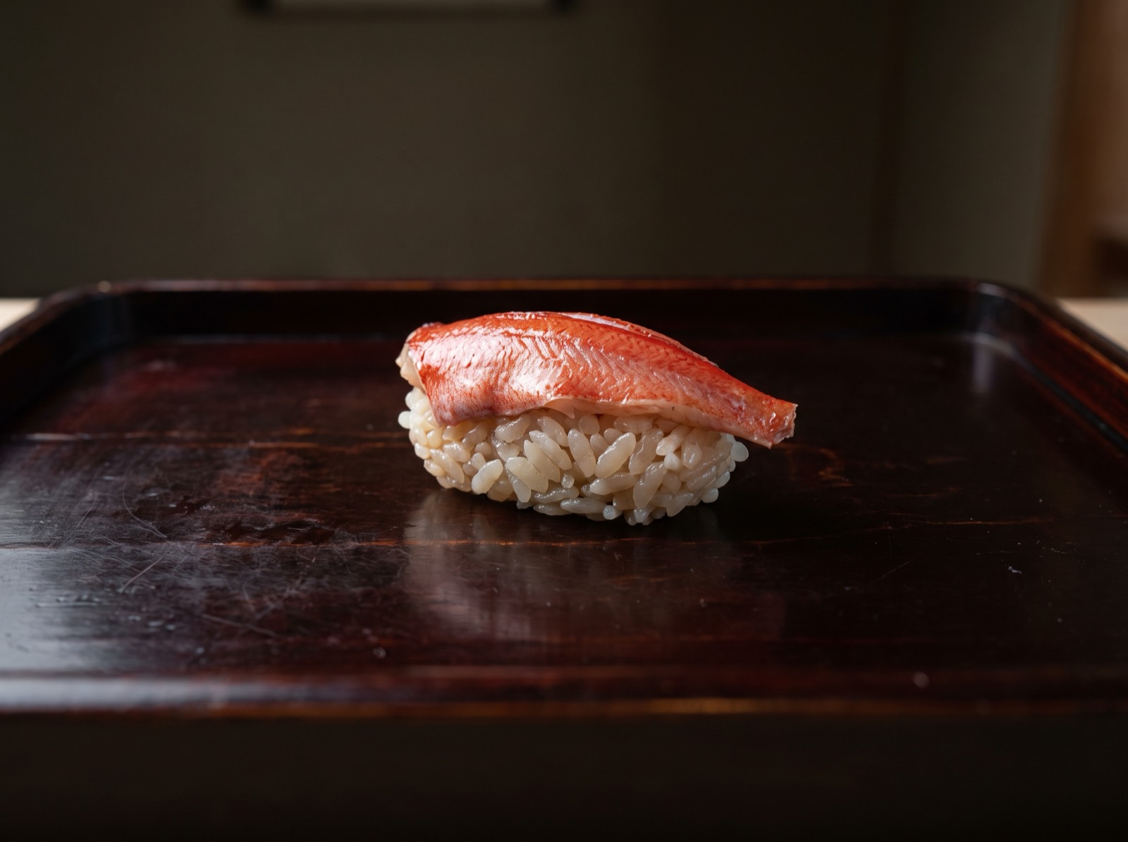 Kasugo nigiri, a whole small young fish visibly smaller than a standard piece.