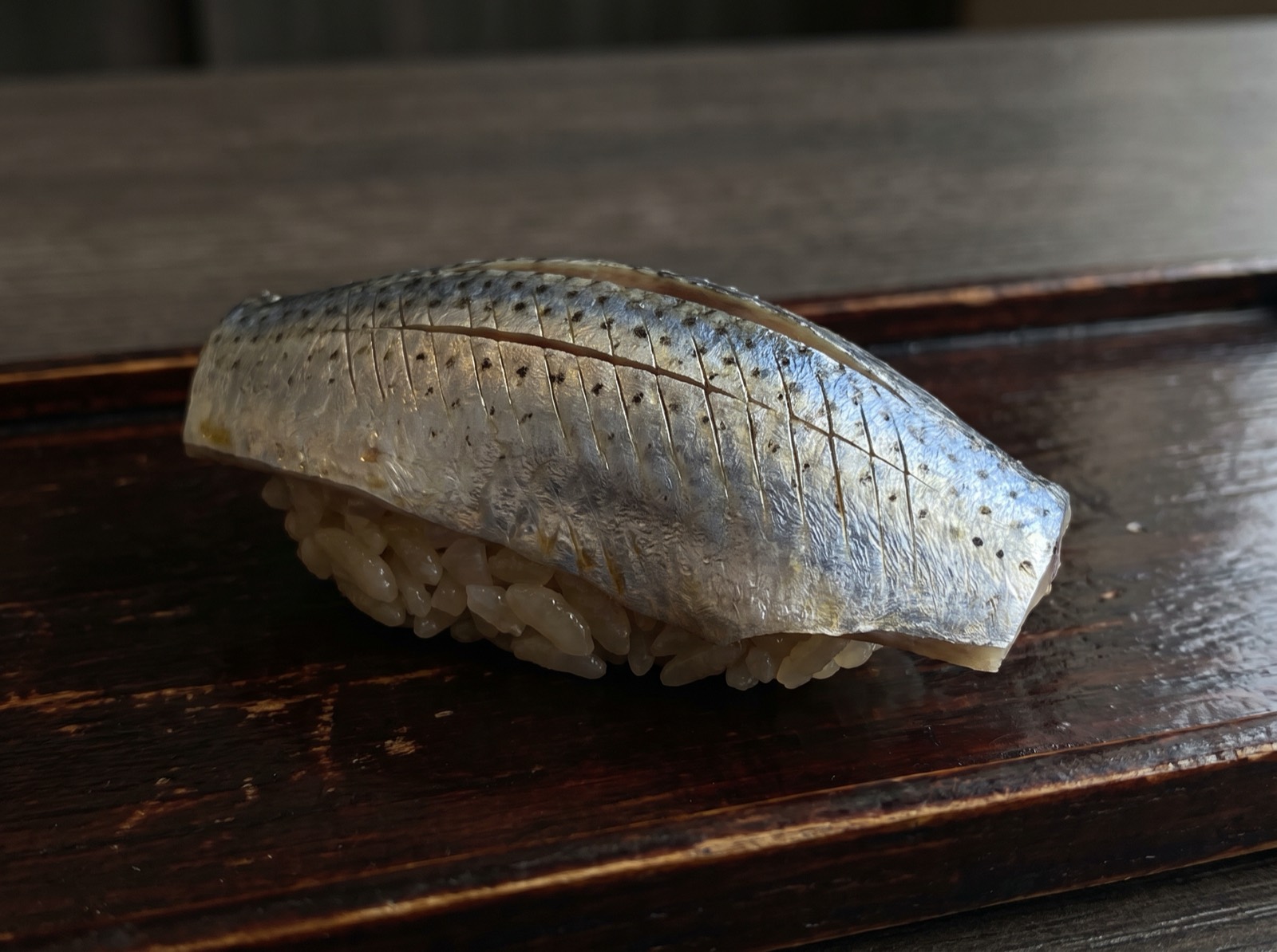 Kohada nigiri, its silver skin scored with fine knife cuts.