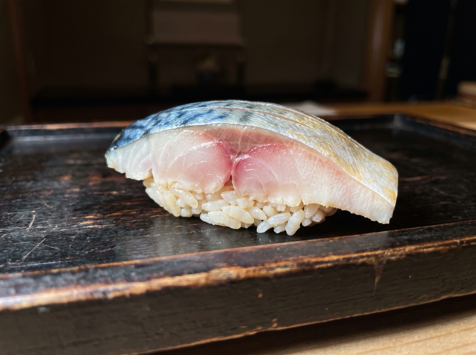 Cured mackerel nigiri, the flesh clouded at the edge.
