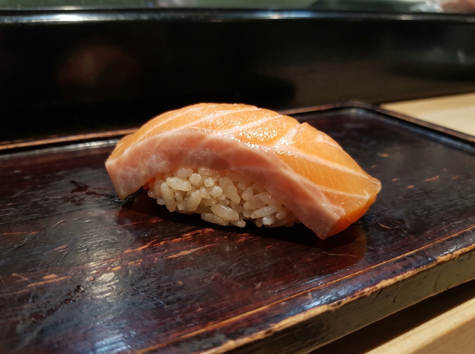 Salmon nigiri, cut to cross the lines of fat.