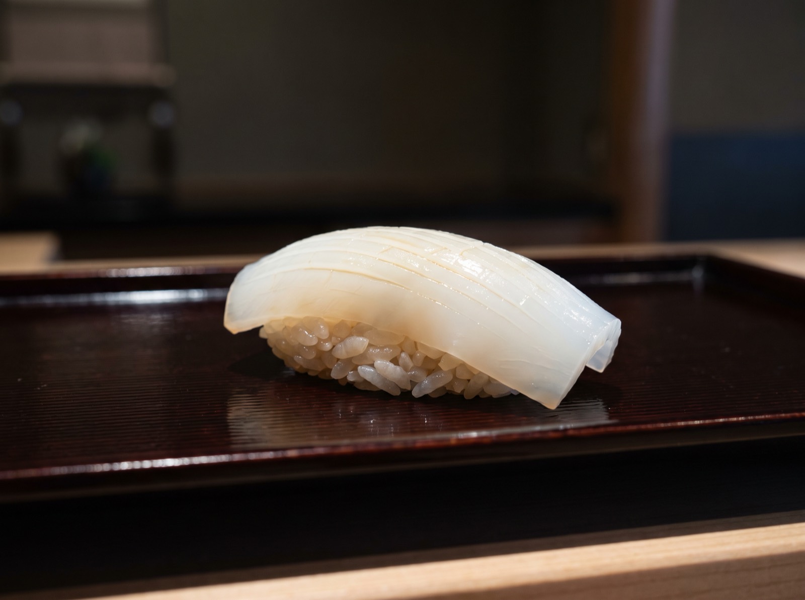 Sumi-ika nigiri, scored with fine parallel cuts.