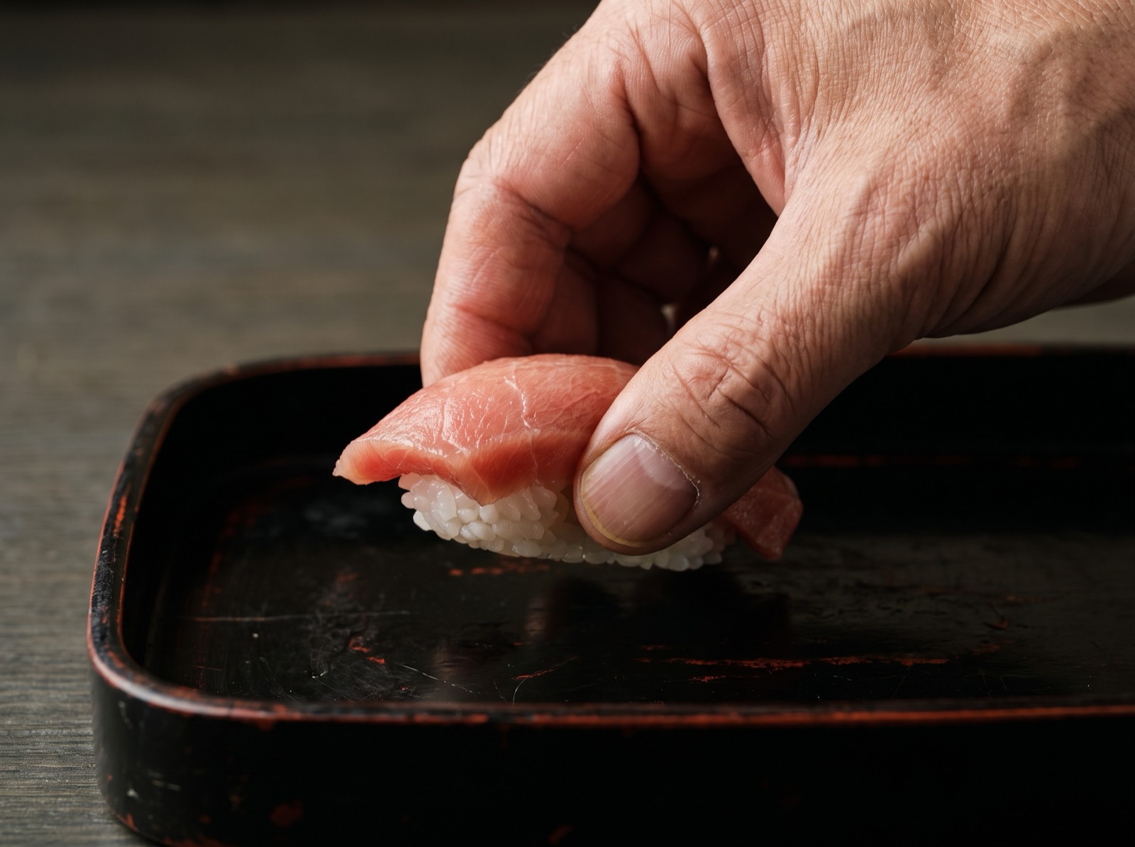 A piece of nigiri picked up from the side with two fingers.