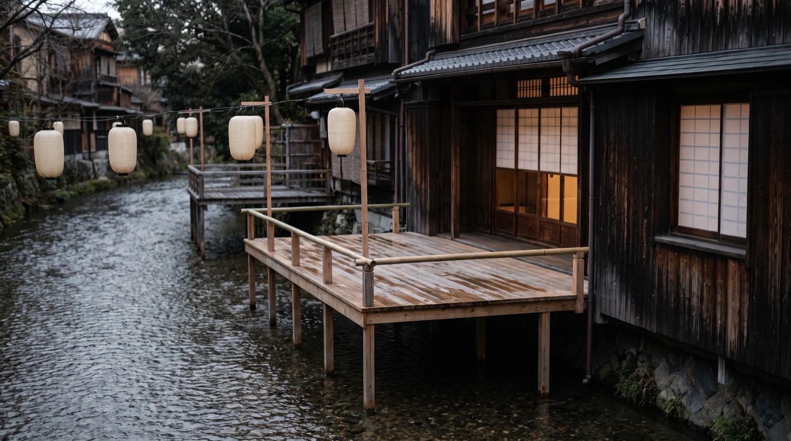 An empty raised wooden dining platform built out over a shallow river channel.