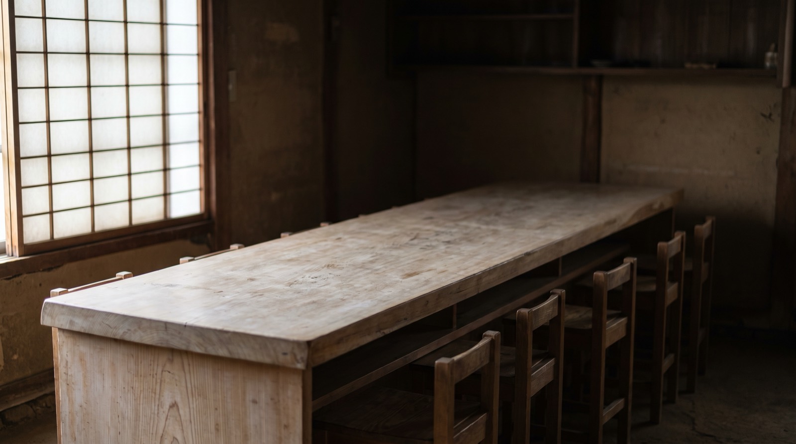 A bare old counter of aged cypress lit through a paper screen.