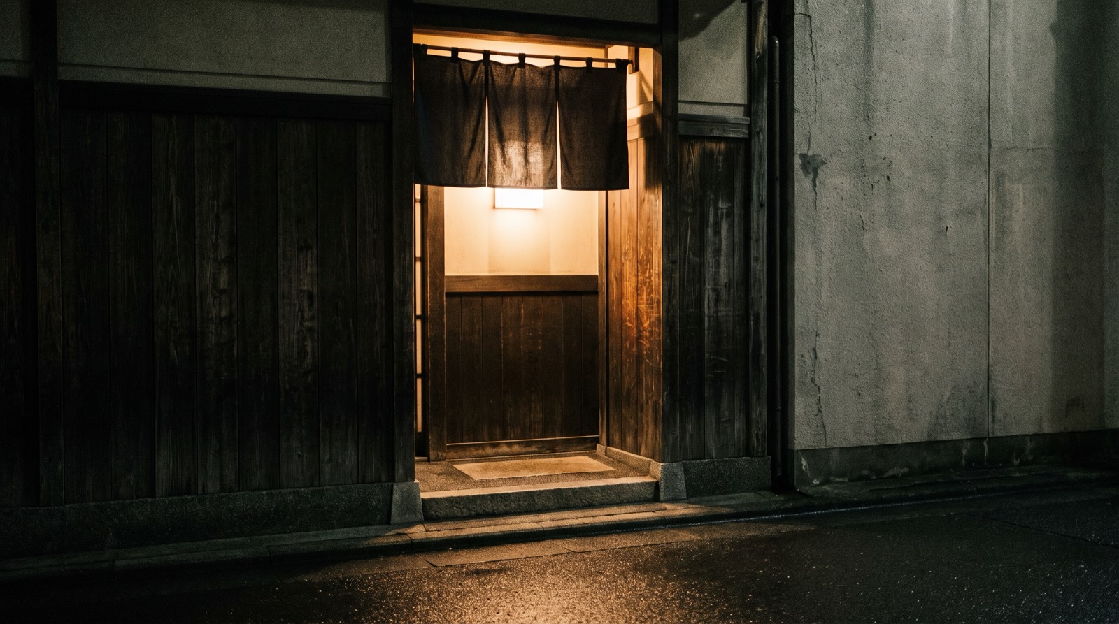 A closed doorway at night with a blank curtain across it and nothing else on the wall.