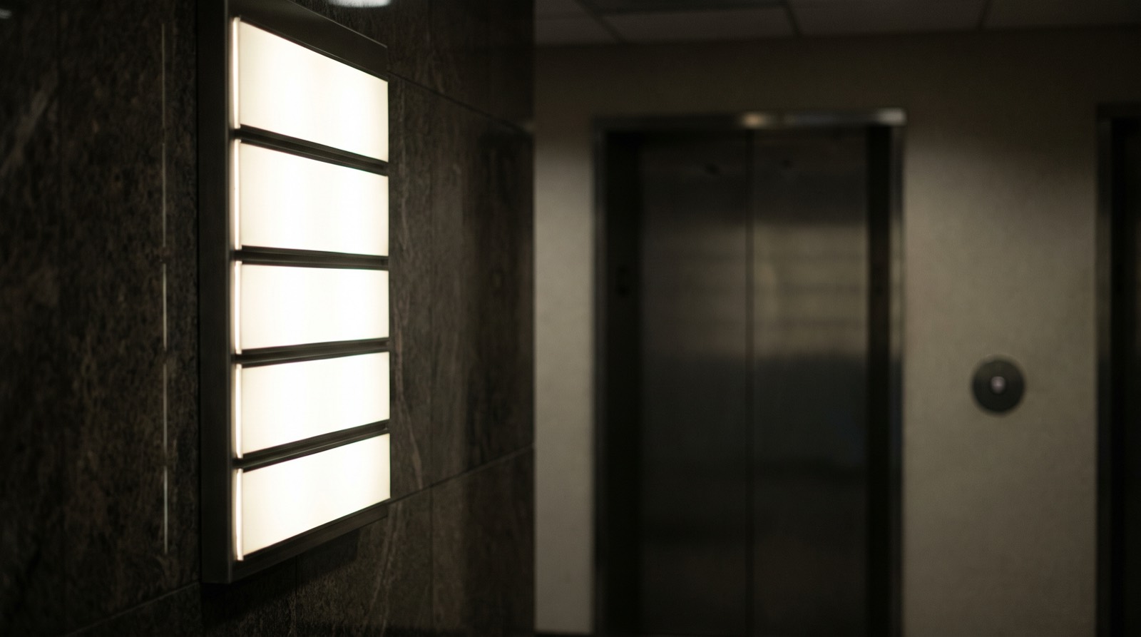 A tenant directory board in a building lobby at night.