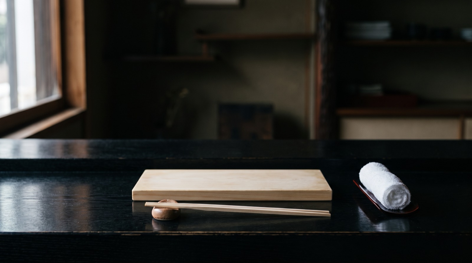 A counter set for one before the meal: serving block, chopstick rest, rolled towel.