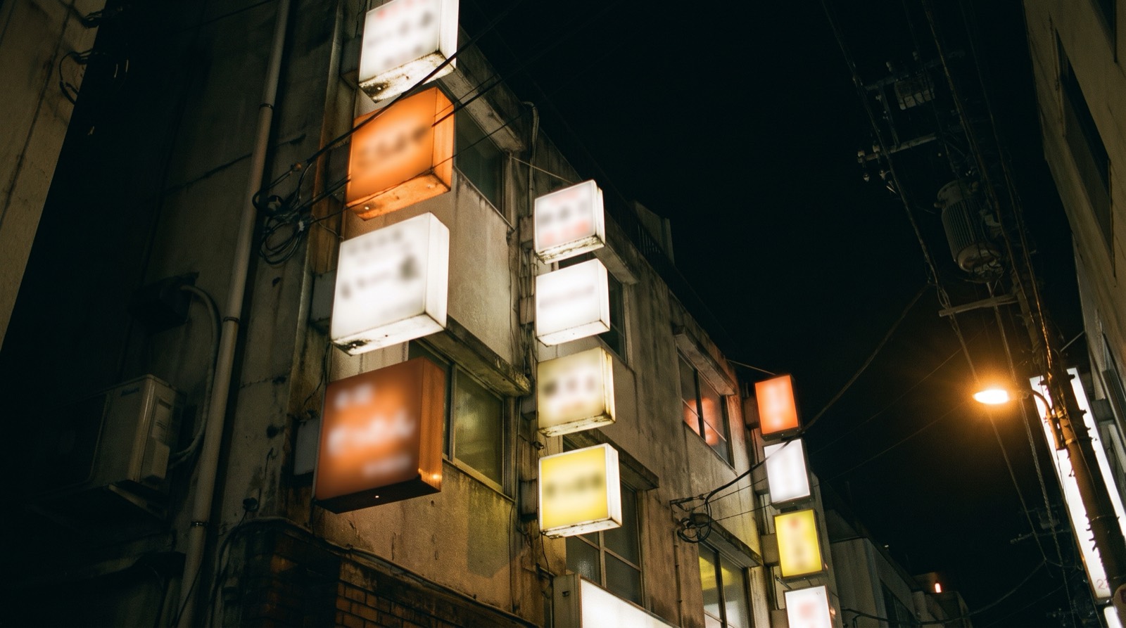 Looking up at the upper floors of a narrow Tokyo building at night.