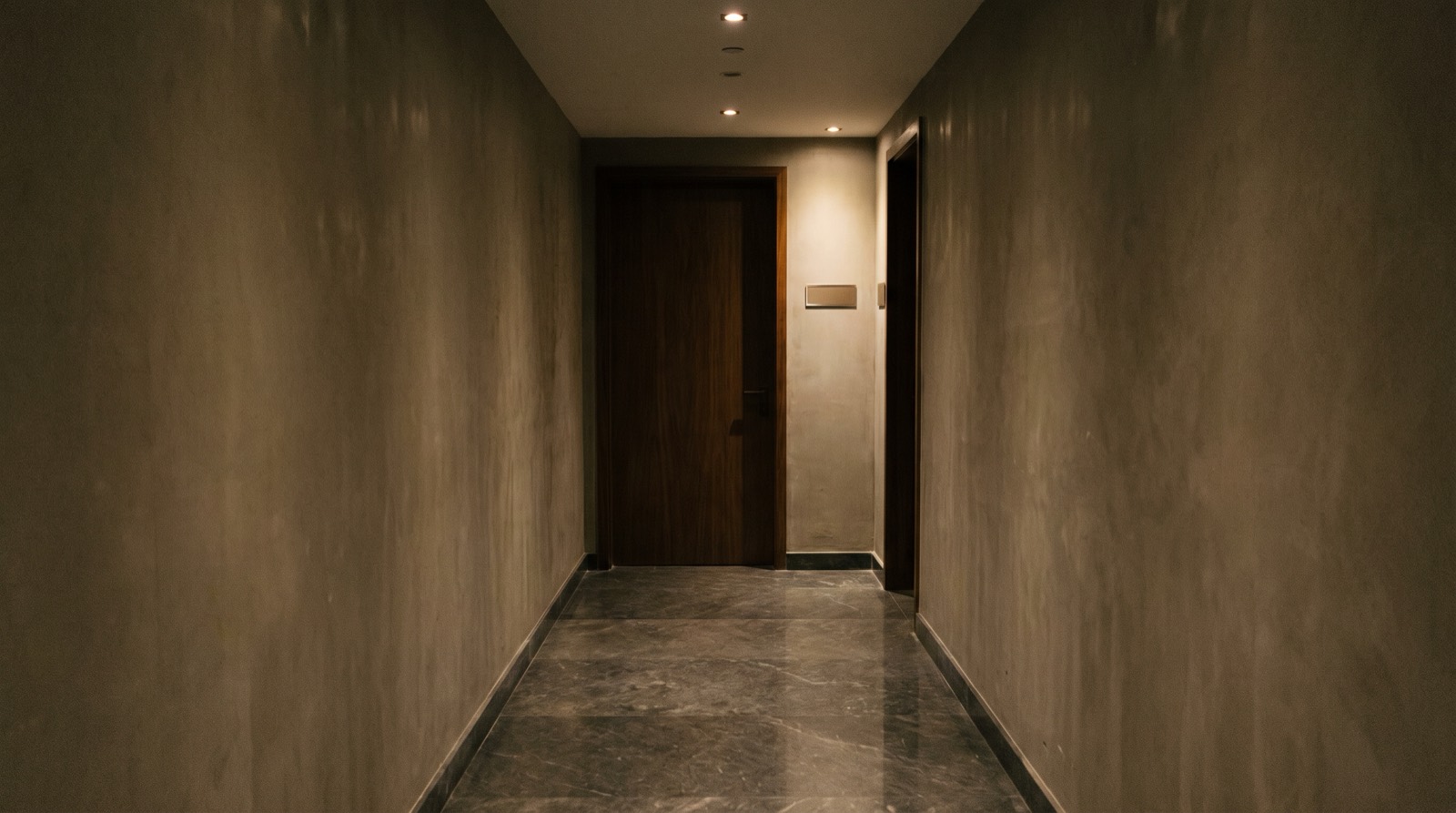 An unmarked door at the end of a basement corridor.