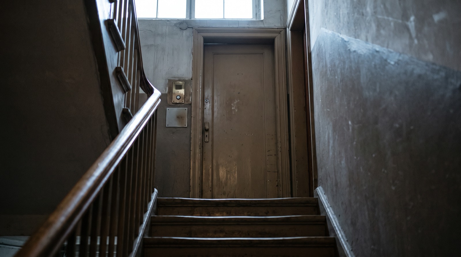 A closed door at the top of a narrow interior stair.
